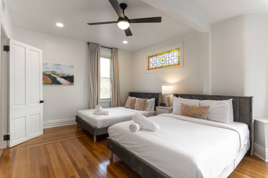 Downstairs bedroom with two beds, a ceiling fan, and a stained glass window.