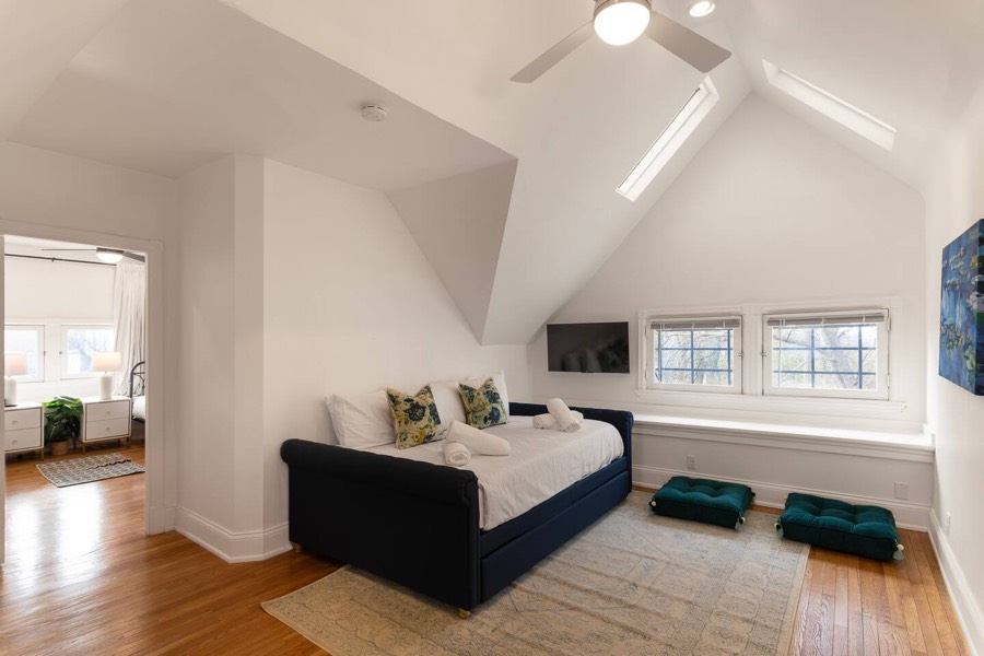 Vaulted top-floor room with an upholstered bed and a ceiling fan.