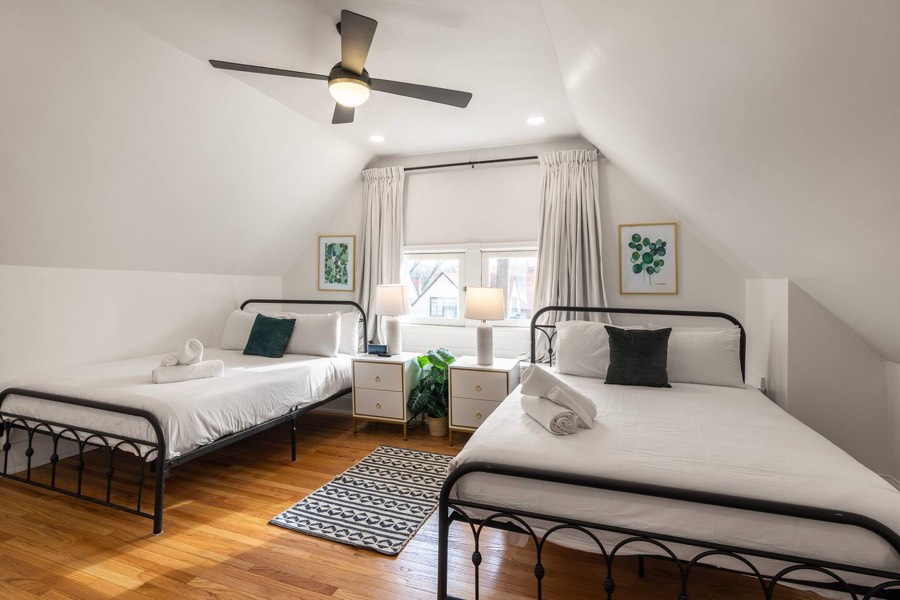 Bedroom with two iron-frame beds and a ceiling fan.