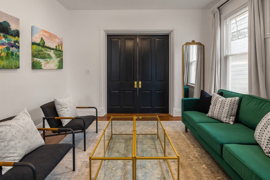 A second sitting room with a green sofa and tall black double doors.