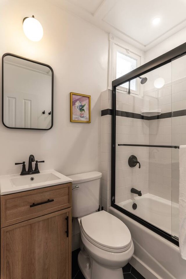 A second bathroom with a wood vanity and a glass shower.