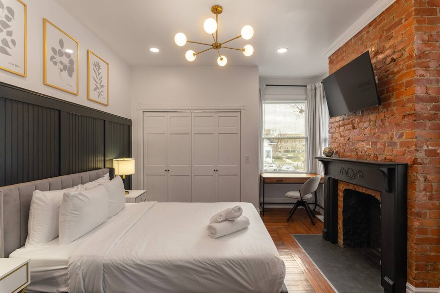 Bedroom with a panelled wall, exposed brick chimney, and a desk in the corner.