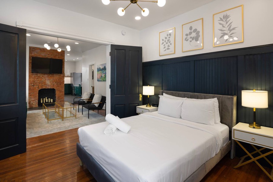 Bedroom with dark panelled walls, a brick chimney breast, and a lamp on each side.