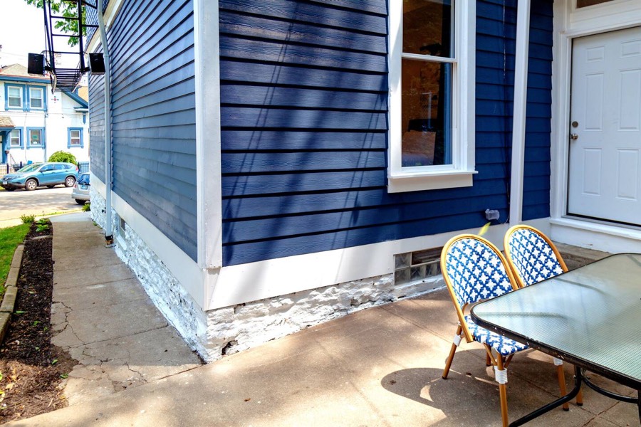 The sidewalk to the rear of the building — one step to the back door, which opens into Unit 1's first bedroom.