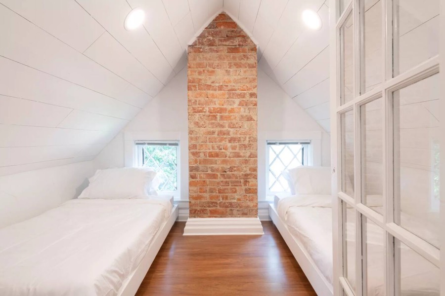 A small but cozy sleeping nook, with exposed brick, shiplap, and 2 twin platform beds