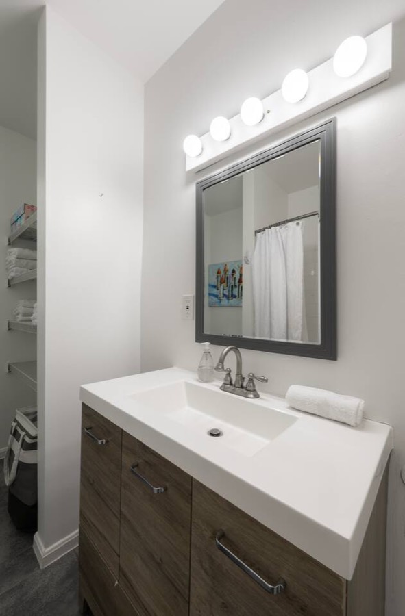 Unit 2's first of two full bathrooms — large vanity, bathtub and shower, and shelving for extra towels